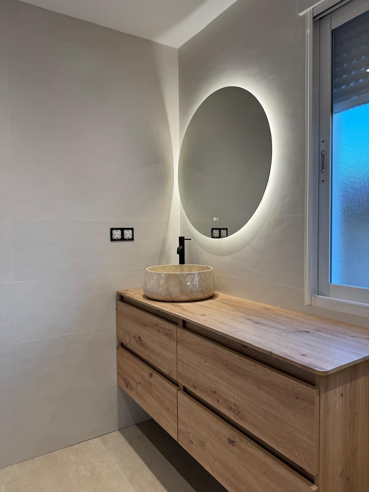 Lavabo de piedra y espejo retroiluminado